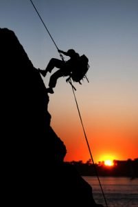 rock climber at sunset time going up a mountain